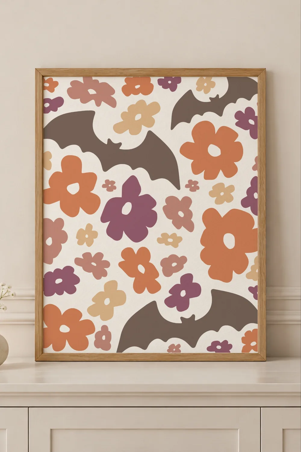 Light wood framed print on a cream dresser with brown bats and orange, plum, pink and tan retro flowers on cream