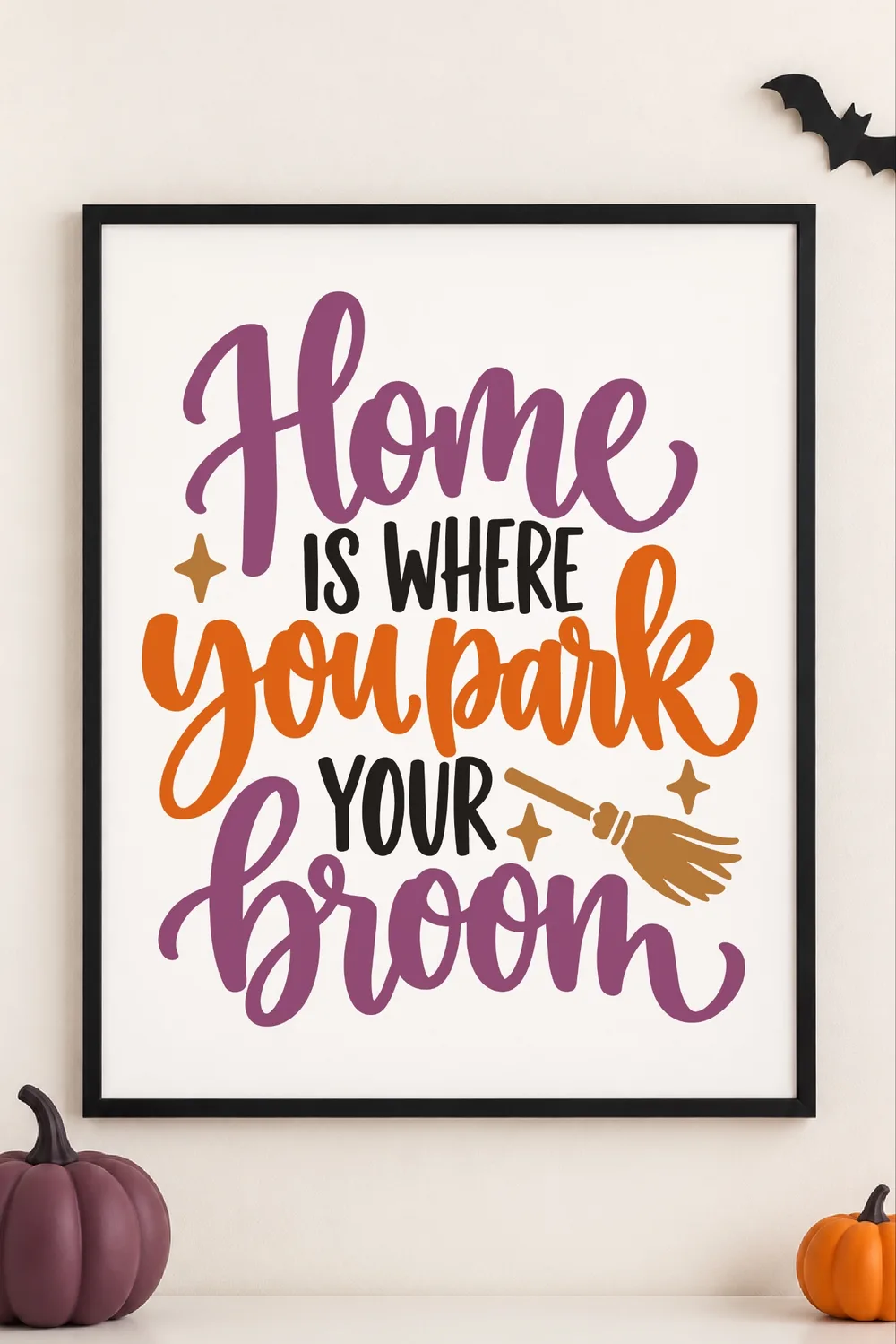 Black framed print with purple, orange and black Home Is Where You Park Your Broom lettering, broom, pumpkins and a bat