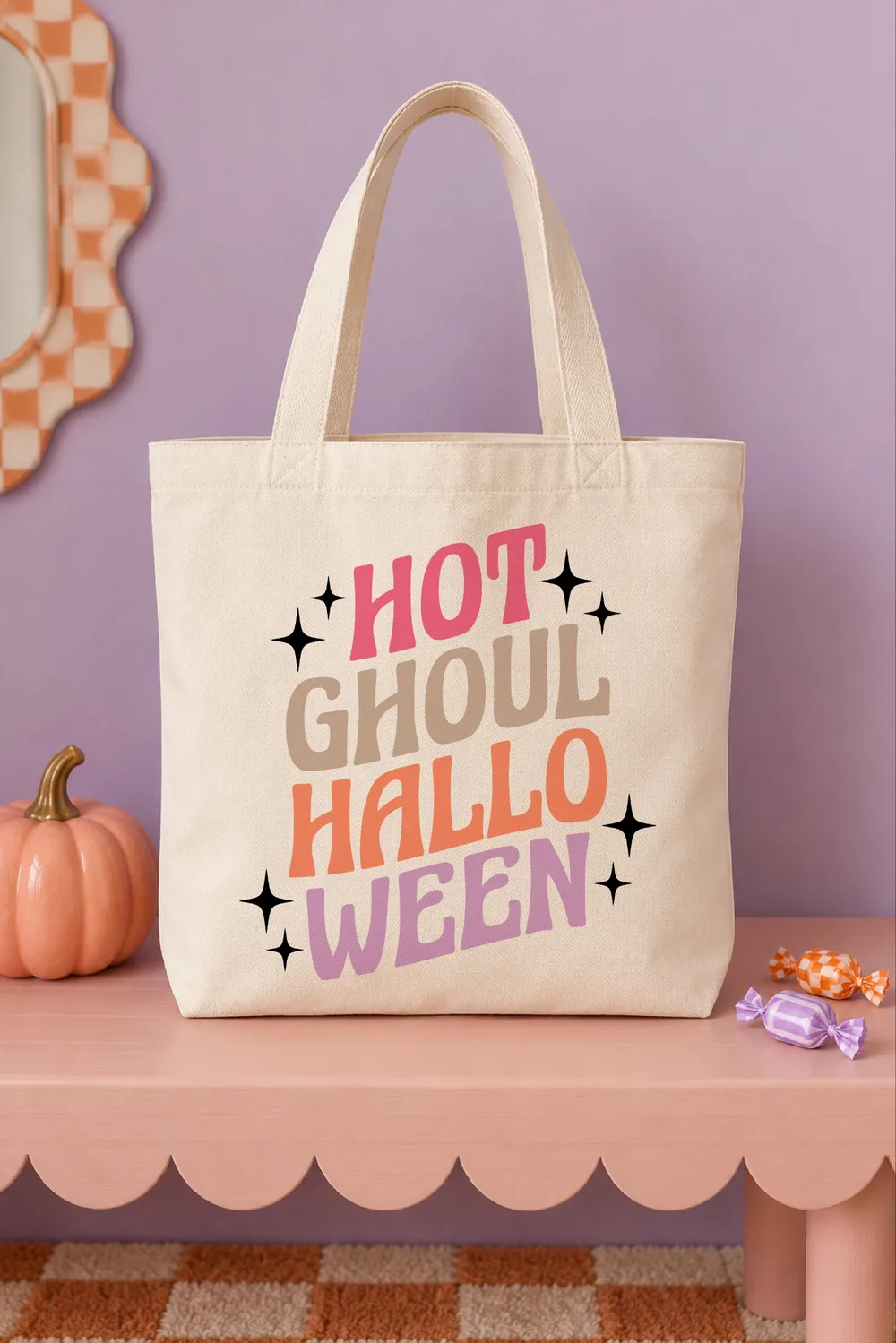 Natural canvas tote bag with Hot Ghoul Halloween in pink, tan, orange and lilac retro letters with black stars, on a pink ben